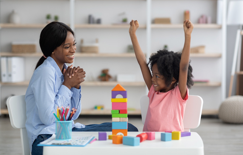 therapist encourages young girl accomplishing a task with blocks
