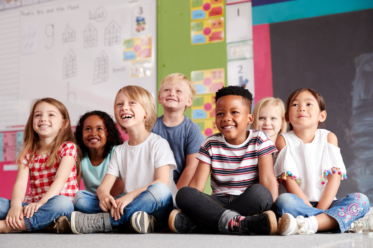 children sit in a classroom smiling