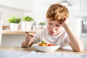 young child with autism looking at a bowl of food