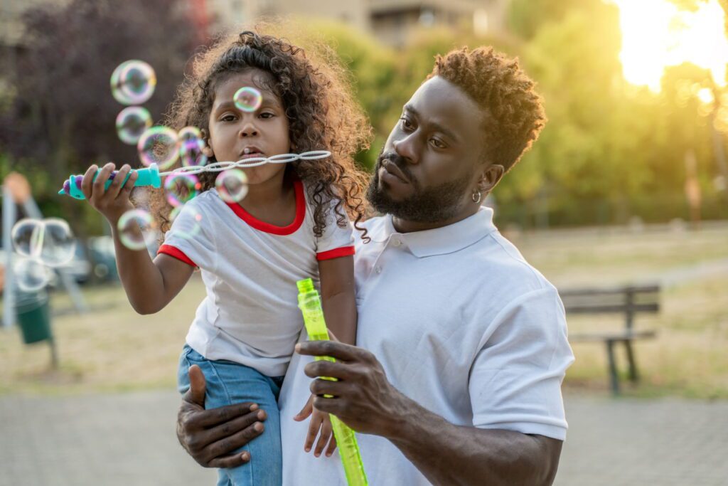 toddler with autism enjoying bubble play with her dad